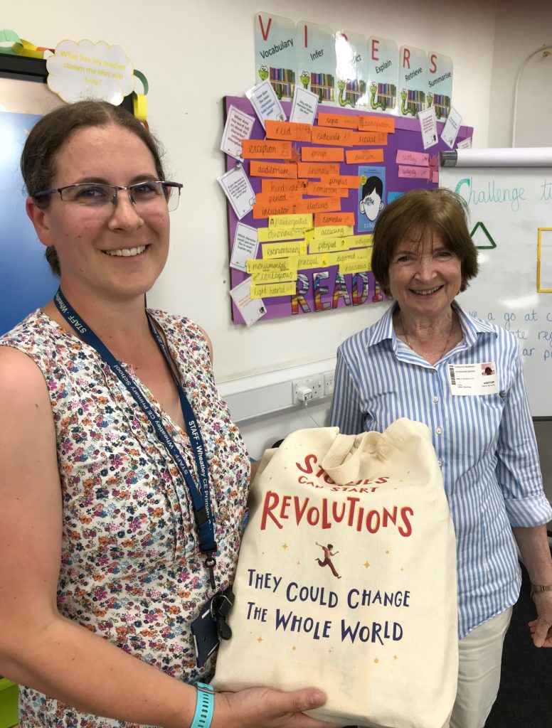 Catherine Matthews presents a bag of books to Jess at Wheatley primary